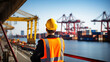 © GustavsMD - An engineer from behind at busy port full with ships and containers