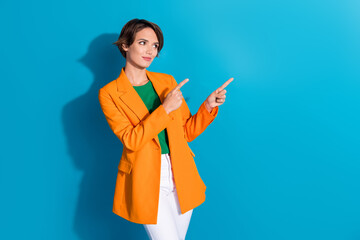 Wall Mural - Photo of young lady orange blazer formal style pointing fingers empty space look for new business company isolated on blue color background