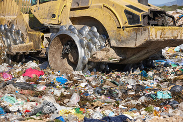 Wall Mural - Heavy machinery shredding garbage in an open air landfill. Pollution management