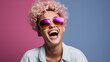© PaulShlykov - Positive young female in trendy sunglasses smiling and looking away while standing against color background