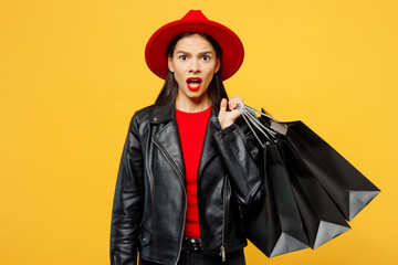 Wall Mural - Young mad furious frustrated disappointed sad upset woman wear casual clothes red hat hold shopping paper package bag look camera isolated on plain yellow background Black Friday sale buy day concept