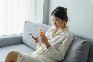 Asian woman Search for information on Internet in smartphone with holding bottled drug. girl reading information online on mobile phone medicine healthcare product concept