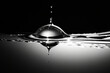 Drop of water is shown in black and white with black background.