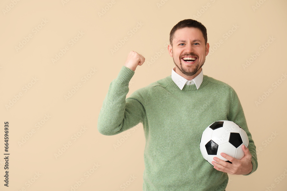Happy man with soccer ball on beige background