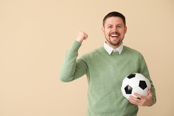 Wall Mural - Happy man with soccer ball on beige background