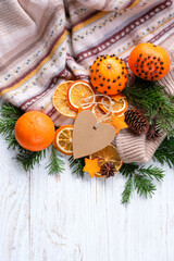 Wall Mural - Christmas holiday background. Knitted sweater, fresh citrus fruits decorated cloves, dry orange slices, fir branches, cones and heart paper card on wooden table. Festive winter season. 