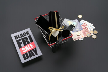 Sticker - Greeting card with text BLACK FRIDAY SALE, shopping basket, gifts, credit cards and money on dark background