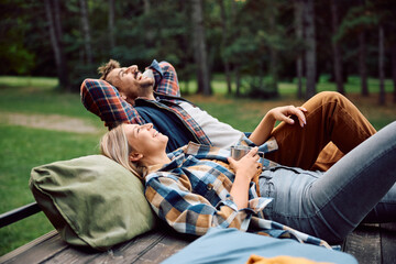 Happy couple of campers enjoying in freedom and fresh air in woods.