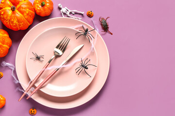 Halloween table setting with pumpkins and spiders on purple background