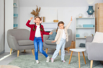 Wall Mural - Cute little girls in headphones dancing at home