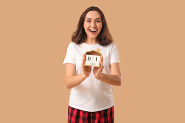 Canvas Print - Beautiful young woman in pajamas with countdown calendar on brown background