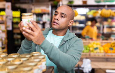 Shopper reads description of canned food at a grocery supermarket