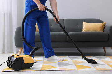 Wall Mural - Dry cleaner's employee hoovering carpet with vacuum cleaner in room, closeup