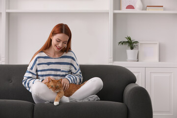 Wall Mural - Happy woman with her cute cat on sofa at home, space for text