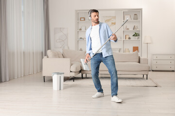 Poster - Happy man in headphones having fun with mop while cleaning at home