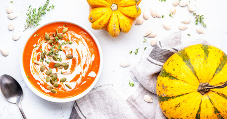 Wall Mural - Pumpkin soup puree with seeds, coconut cream and thyme.. Autumn slow comfort food.  Healthy vegan eating. White soup bowl on gray table background. Top view