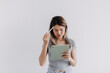 © Suthida - Asian Thai woman wear grey, hands holding tablet and white pen, touching head, thinking hard, no idea suspicious, doubt face while working and looking at computer, isolated on white background.