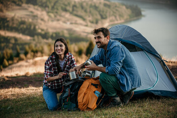 Wall Mural - A diverse couple happily preparing for a cooking on a camp stove on a sunny camping day