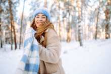 Smiling Woman In A Winter Snow-covered Park Walks And Plays With Snow On A Beautiful Sunny Day. Young Fashionable Woman In The Winter Forest. Walking Concept, Weekend.