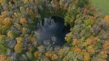 Slowly Approaching Aerial View Of The Water-filled Kaali Meteorite Crater Surrounded By Colourful Trees In Autumn. Saaremaa, Estonia.