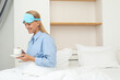 © Atlas - Young woman in sleeping mask drinking coffee in bed