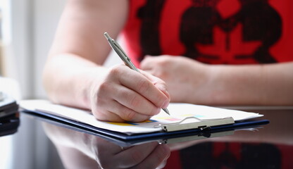 Male arm in suit and tie fill form clipped to pad with silver pen closeup. Sign gesture read pact sale agent bank job make note loan credit mortgage investment finance chief legal law concept