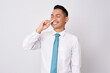 © Bangun Stock Photo - Young Asian businessman wearing a formal shirt and tie shows a relieved expression when using nasal stick inhaler isolated on white background