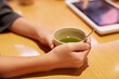 喫茶店でお茶を飲みながら注文する女性の手のアップ写真