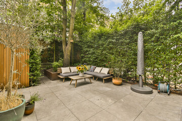 an outdoor living area with patio furniture and trees in the back yard, surrounded by lush green foliage on a sunny day