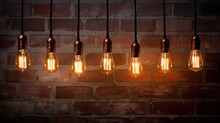 A Collection Of Decorative Antique Edison-style Light Bulbs Showcased Against A Textured Brick Wall Backdrop.
