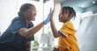 © Gorodenkoff - Young African American Boy Sitting In The Chair In Bright Hospital And Getting His Flu Vaccine. Female Black Nurse Is Finished Performing Injection. Professional Woman High-Fives A Kid For Being Brave