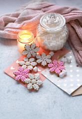 Wall Mural - cozy Christmas background. Snowflake gingerbread cookies, candle, jar with marsmallows and knitted scarf on table. Festive winter season concept. Christmas, New year holidays