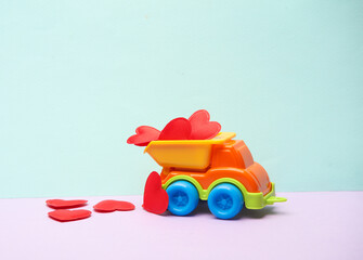 Wall Mural - Toy dump truck with red hearts on a pastel background. Love concept