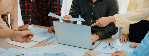 Professional engineer team discussion about house design on meeting table with architectural equipment and blueprint scatter around at modern office. Focus on hand. Closeup. Delineation.