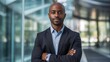 © Krtola  - Portrait of a mid adult African American businessman in front of a modern corporate glass building