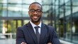© Krtola  - Portrait of a mid adult African American businessman in front of a modern corporate glass building