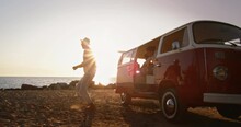 Slow Motion Portrait of Group of Young Friends Jumping out of a Minivan and Celebrating by Dancing on a Beach. Active Men and Women Having Fun, Enjoying Their Youth and Summer Warm Days