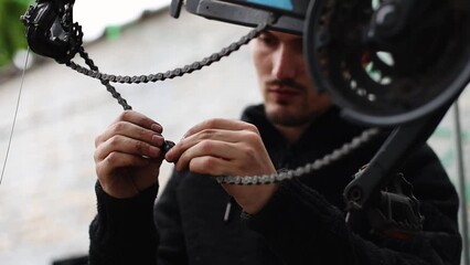 Wall Mural - A young man connects a bicycle chain.