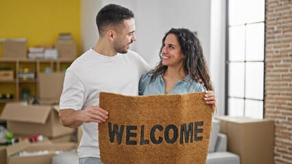 Poster - Man and woman couple holding welcome doormat kissing at new home