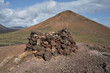 View of a cairn or pile of rocks and a volcano in Timanfaya National Park, Lanzarote, Canary Islands, Spain.