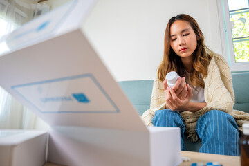 Female sick checking ingredient information on sofa at house, Sick ill young woman she covered blanket hold pills bottle read medicine prescription label before eating, pharmacy healthcare medicament