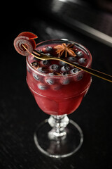 Wall Mural - Glass with red alcoholic cocktail with blueberries and allspice, decorated with fresh sweet pastille