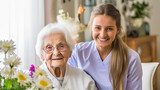 Fototapeta  - Social medical worker supports and visits pensioner woman in living room of house in atmosphere of comfort. Smiling happy senior adult woman and caregiver in nursing home for the elderly