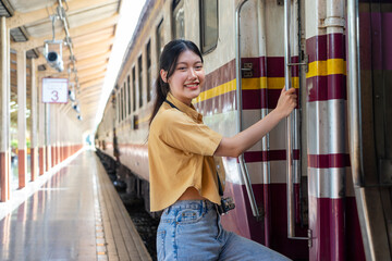 Happy young traveler woman with luggage getting off the train at train station platform