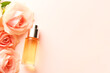Spa relax composition with cosmetic dropper bottle with rosses oil or perfume and roses on tender pink background. Natural skin care treatment. Mock up of beauty product based on roses. Copy space