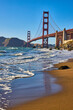 Waves on wet sandy beach below Golden Gate Bridge