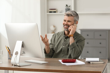 Wall Mural - Professional accountant talking on phone and working at wooden desk in office