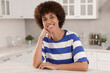 © New Africa - Happy young woman sitting at table in kitchen