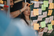 © qunica.com - Diverse business professionals brainstorm and collaborate using adhesive notes, glass walls, and creative ideas in a vibrant office. Successful teamwork, growth, and planning in a co-working space.
