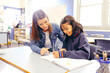 © Austockphoto - Aboriginal female school teacher sitting with her student in the classroom